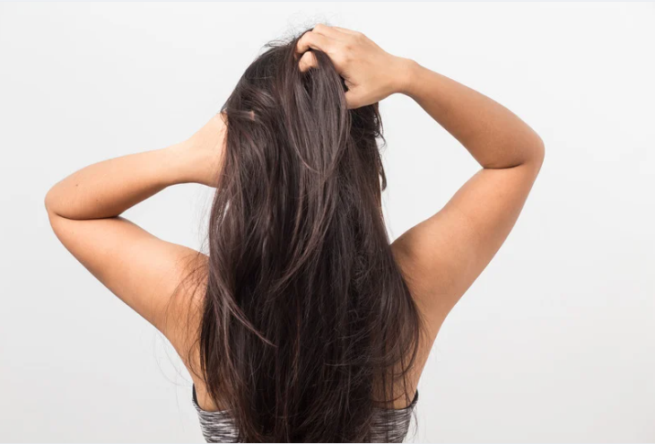 Woman touching scalp with long healthy dark hair